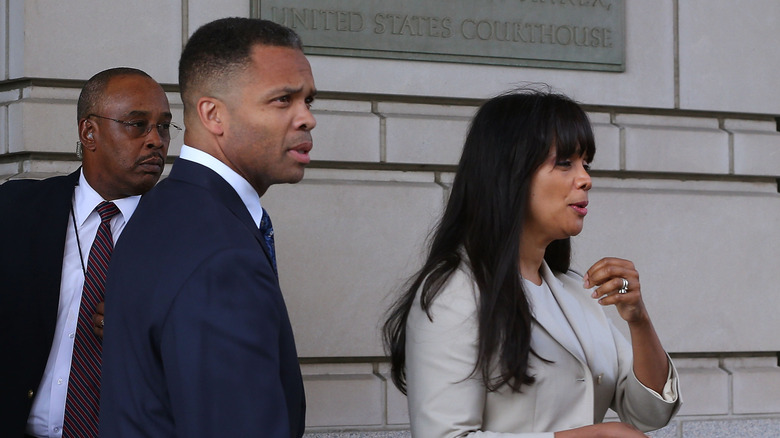 Jesse Jackson Jr. in a suit beside wife, Sandi Jackson outside of a courthouse.