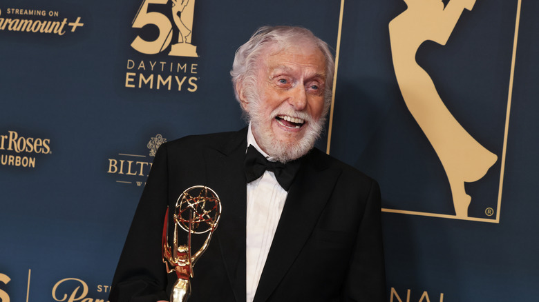 Dick Van Dyke smiling and looking to the side while holding an Emmy.