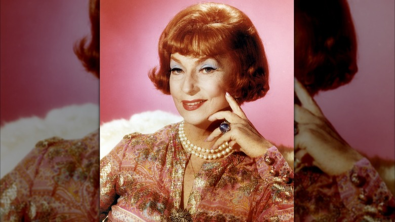 Agnes Moorehead smirks while placing a hand on her face