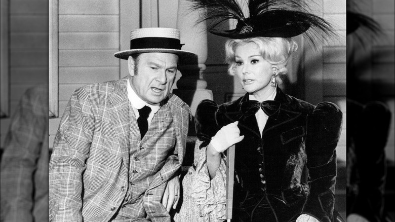 Eva Gabor poses next to her costar in an elaborate velvet coat
