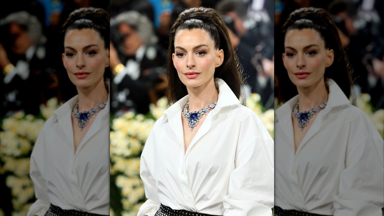 Anne Hathaway in white shirt wearing her hair in a high voluminous ponytail