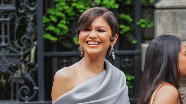 Zendaya smiling and walking with short hair