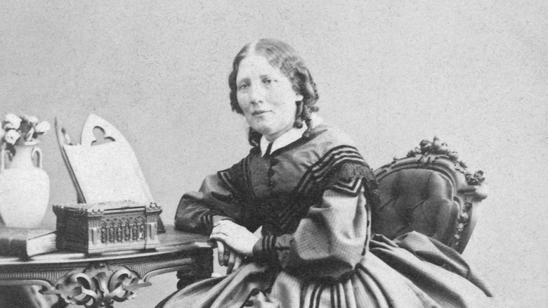 Harriet Beecher Stowe sitting with her hands together and elbow on the desk
