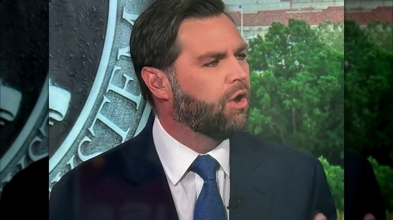 JD Vance screenshot with a sigil behind him, captured mid-talk.