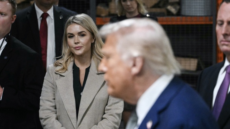 Karoline Leavitt stares at Donald Trump as he speaks to members of the media at the Kennedy Center for the Performing Arts in Washington, DC (2025)
