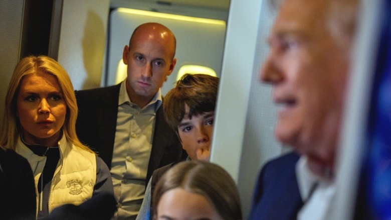 Karoline Leavitt looks on as Donald Trump speaks to members of the media aboard Air Force One following a trip to Scotland (2025)