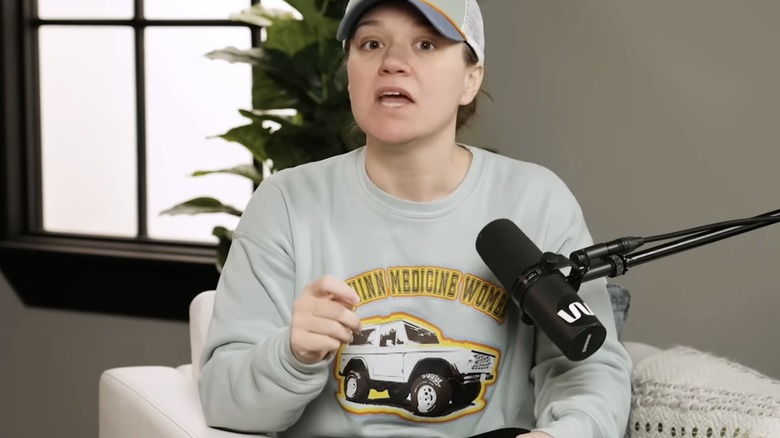Kelly Clarkson makeup free wearing sweatshirt and trucker hat