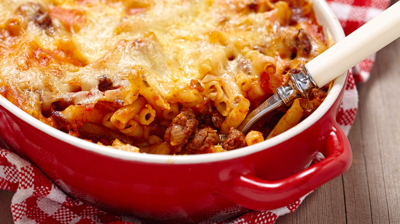 a casserole dish filled with baked mostaccioli with a meat sauce