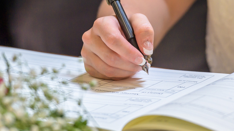 a hand signing a funeral registry