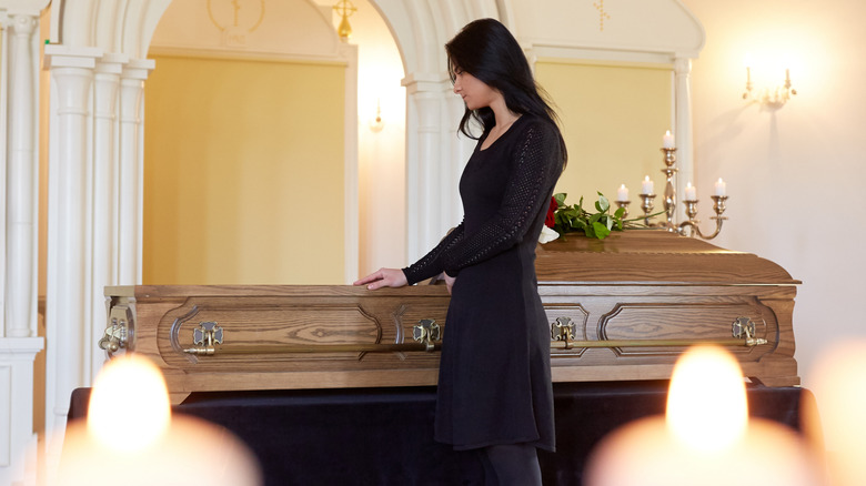 A woman standing next to an open coffin