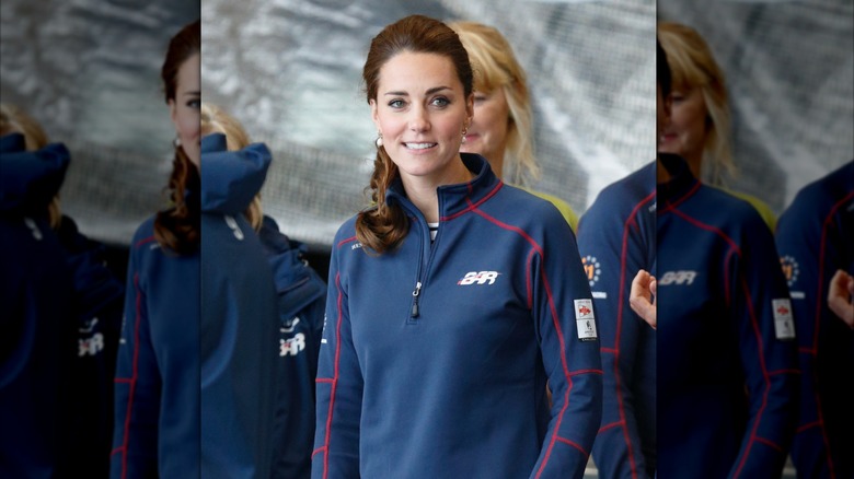 Kate Middleton smiles in a navy blue pullover.