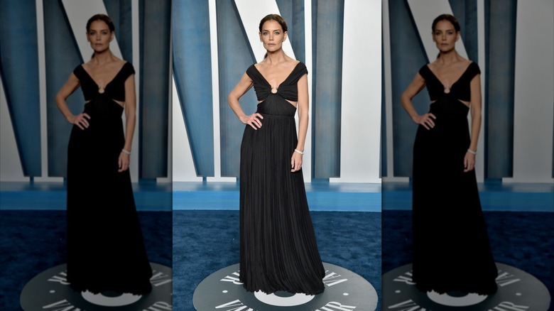 Katie Holmes in a black dress with a hand on her hip