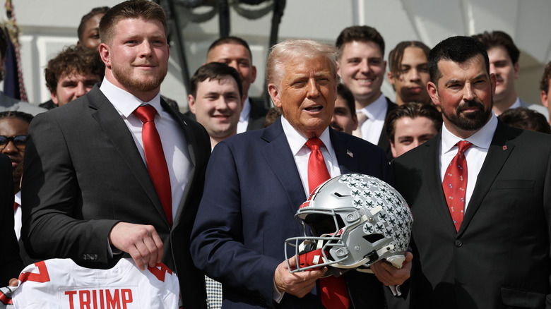 Donald Trump with Navy football team holding helmet