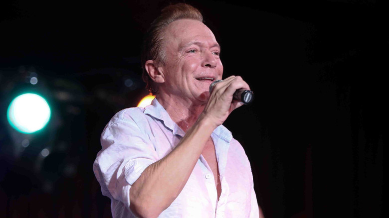 David Cassidy in white outfit holding a microphone on stage