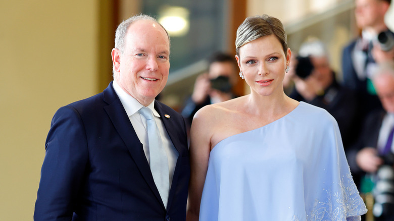 Princess Charlene in a one-shoulder powder blue outfit beside Prince Albert II