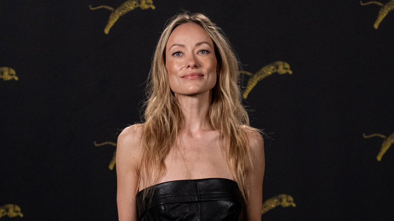 Olivia Wilde in a strapless black dress against black background