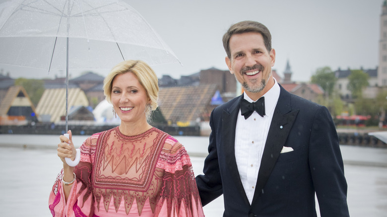 Princess Marie-Chantal of Greece holding an umbrella beside Crown Prince Pavlos