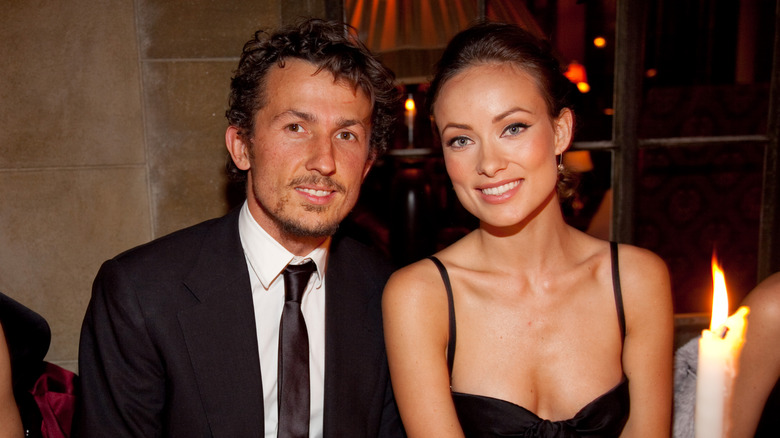 Olivia Wilde in a strappy black dress beside husband Tao Ruspoli