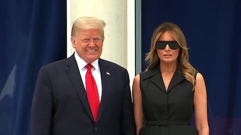 Donald Trump smiles while Melania Trump slightly curls her lip up at the Saint John Paul II National Shrine.