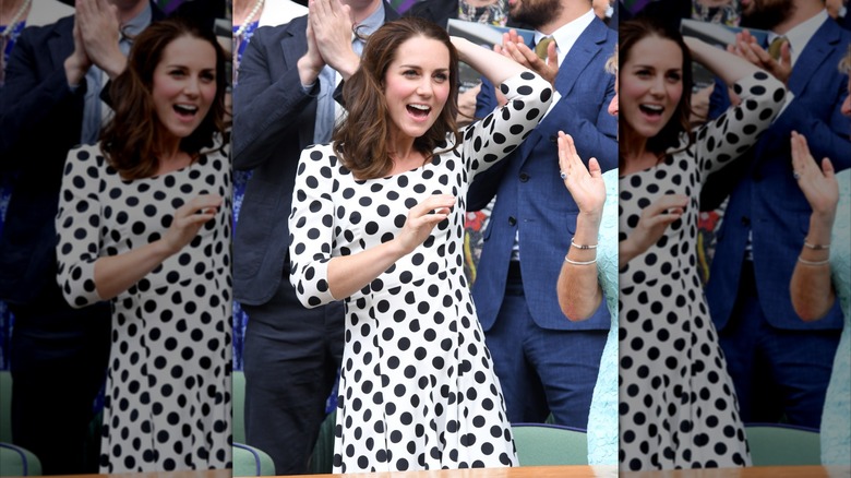 Kate Middleton holding her hair back in a white-and-black polka dot dress.