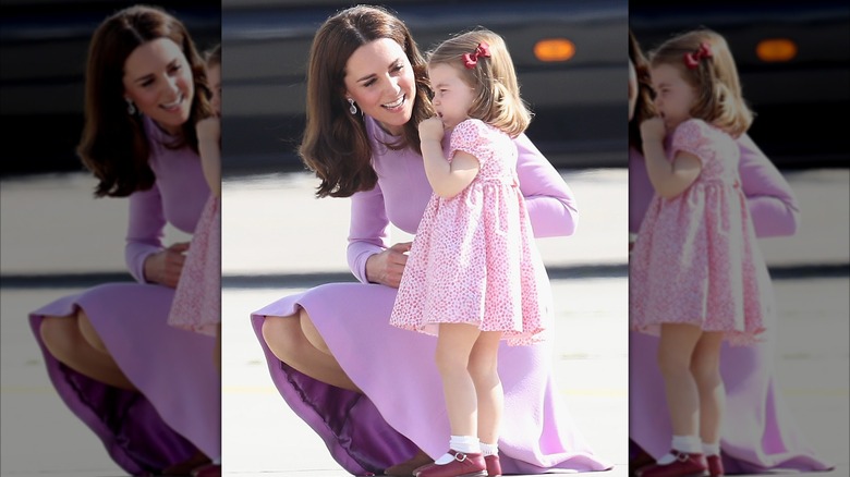 Kate Middleton leaning down to smile at Princess Charlotte.