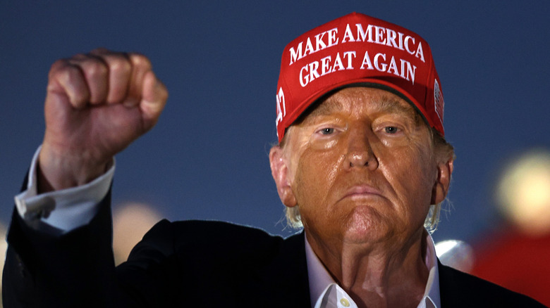 Donald Trump at night wearing a Make America Great Again cap.