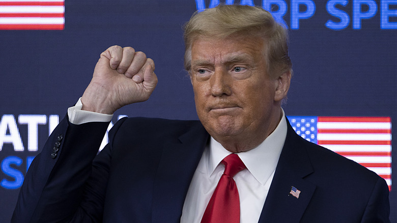 Donald Trump with a serious expression and a raised fist.