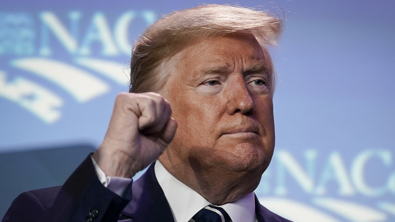 Donald Trump with his hand partially blocking his face.