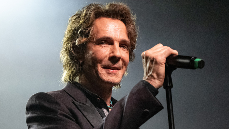 Rick Springfield smiling in front of a microphone
