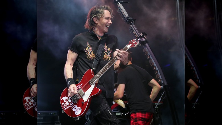 Rick Springfield smiling as he plays the guitar