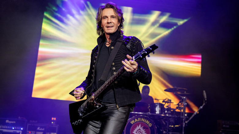 Rick Springfield smiling and playing the guitar on stage