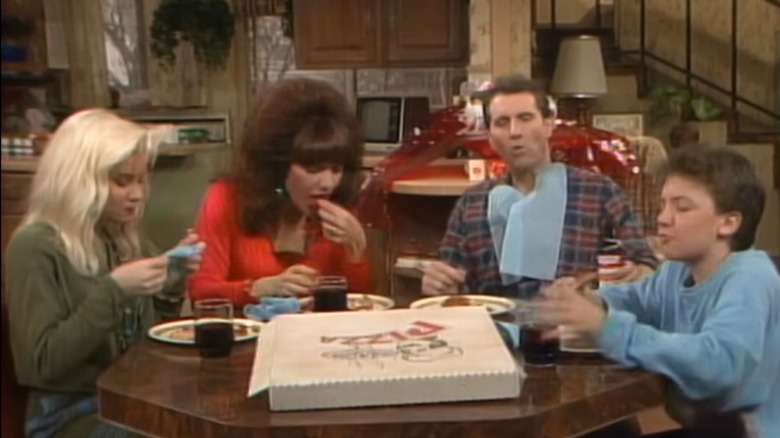 The Bundy family sit around the table and eat pizza in "Married... with Children"