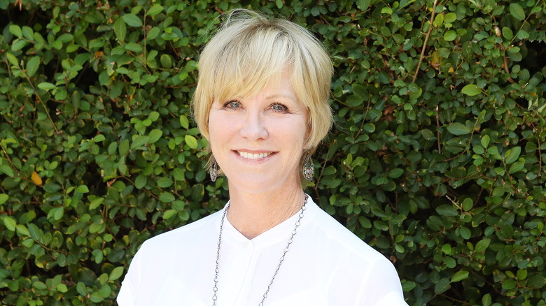 Joanna Kerns in white top smiling with short hair and silver chain