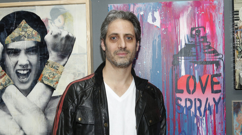 Josh Saviano posing in front of paintings
