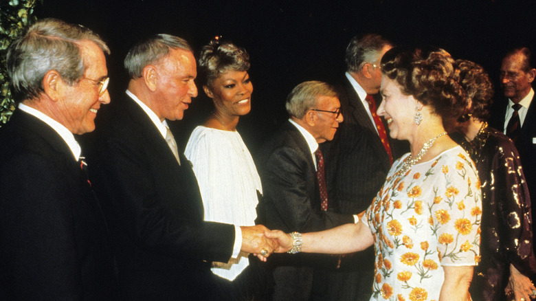 Queen Elizabeth ll shakes hands with singer Frank Sinatra watched by Perry Como and Dionne Warwick at a dinner at the studios of 20th Century Fox in Los Angeles on the 27th of February 1983.