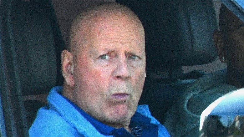 Bruce Willis sitting in a car with a furrowed brow in 2025 wearing a blue sweater