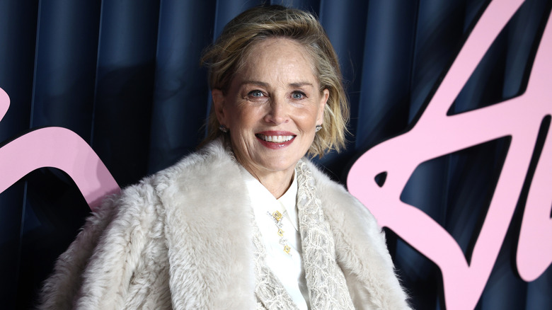 Sharon stone in white fur coat and white shirt smiling at the 2025 Fashion Awards