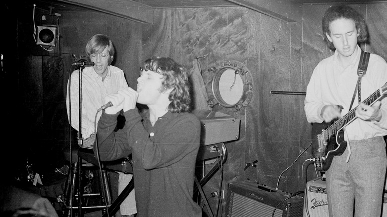 Jim Morrison singing into a microphone during a performance with The Doors