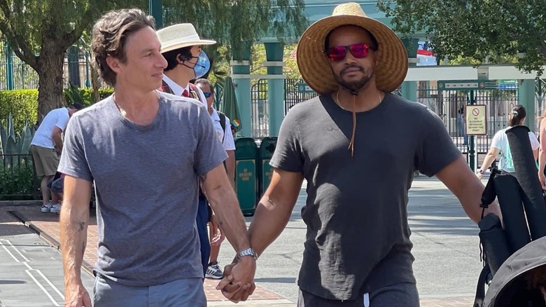 Zach Braff and Donald Faison holding hands and walking through Disney Land.