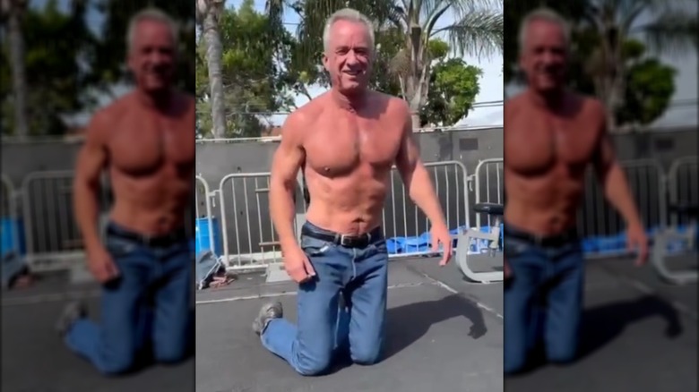 Robert F. Kennedy Jr. on his knees outdoors, shirtless and wearing blue jeans.