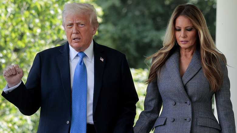 Donald Trump raises a fist as Melania Trump looks down beside him outside the White House.