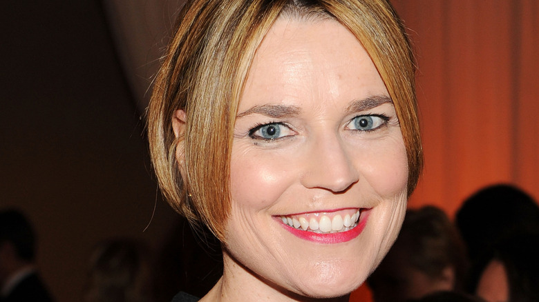 Smiling Savannah Guthrie with cropped hair and coral red lipstick