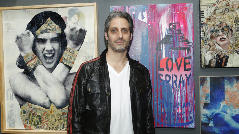 Josh Saviano standing in front of paintings at an art event