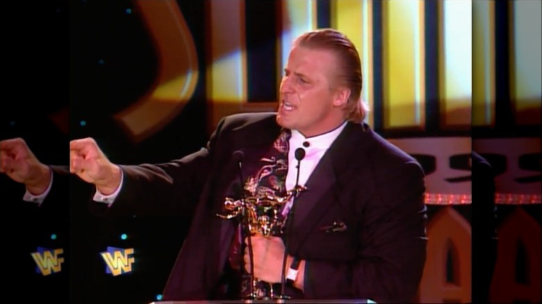 Owen Hart stealing a Slammy Award and pointing at the audience
