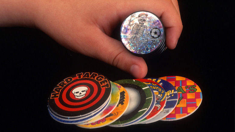 A hand holding discs in a POGs game.