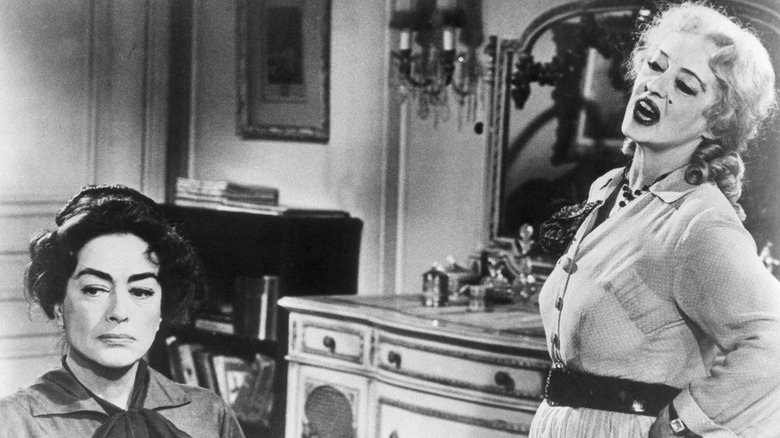 Joan Crawford looking in the distance while Bette Davis talks to her