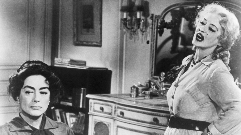 Joan Crawford looking in the distance while Bette Davis talks to her