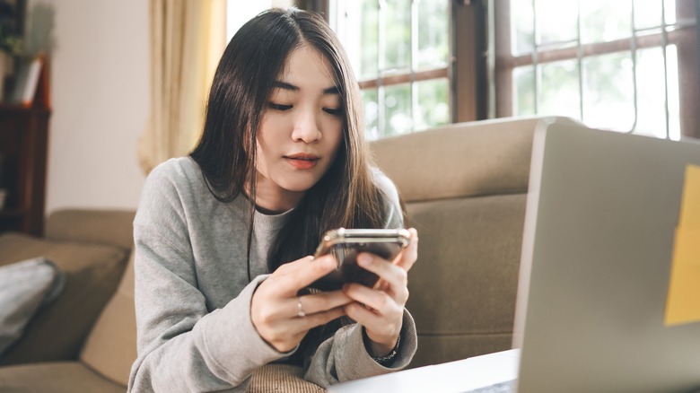 woman texting while on computer