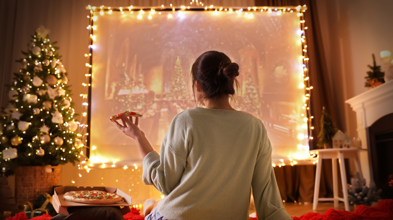 Woman eating pizza and watching Christmas movie