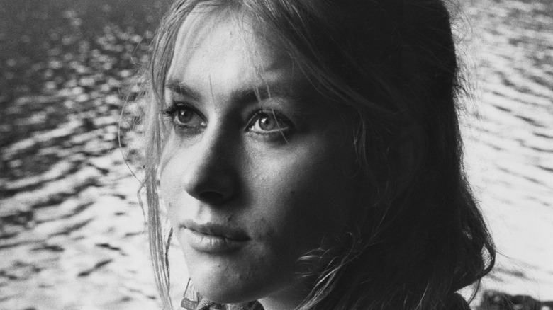 Young Helen Mirren posing by a tree